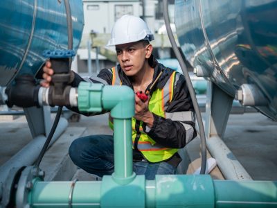 Focused industrial engineer using a calibration tool to check equipment at a manufacturing plant, ensuring operational efficiency.